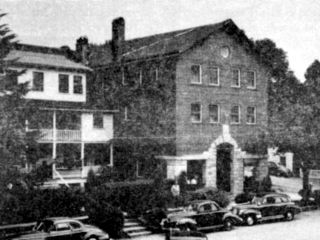 A Black And White Photo Of A Building With Cars Parked In Front