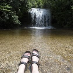 A Pair Of Feet In Front Of A Waterfall